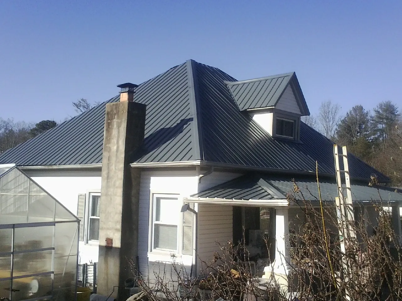 Dark blue standing seam metal roof on a white farmhouse with dormer — Slate & Tile Roof Repair by Roofing Brothers in Glendale Heights