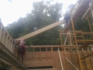 Carpenter raising a rafter beam on a new second story frame in Glendale Heights