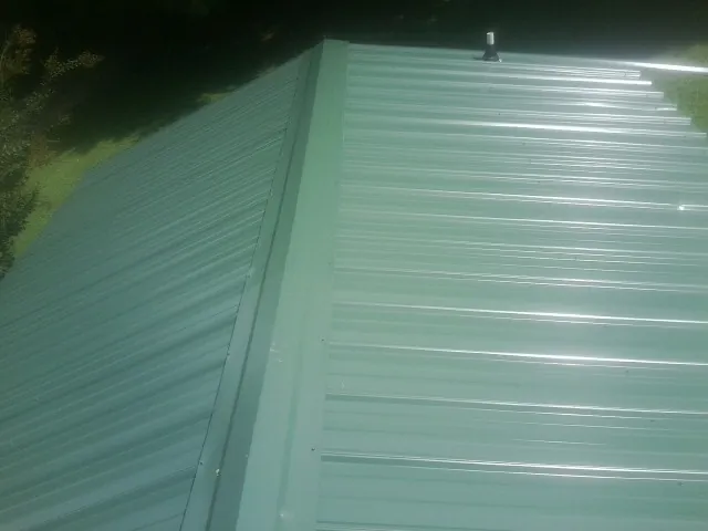 New green metal panels meeting at the ridge of a roof — Flat Roof Repair work by our crew in Glendale Heights