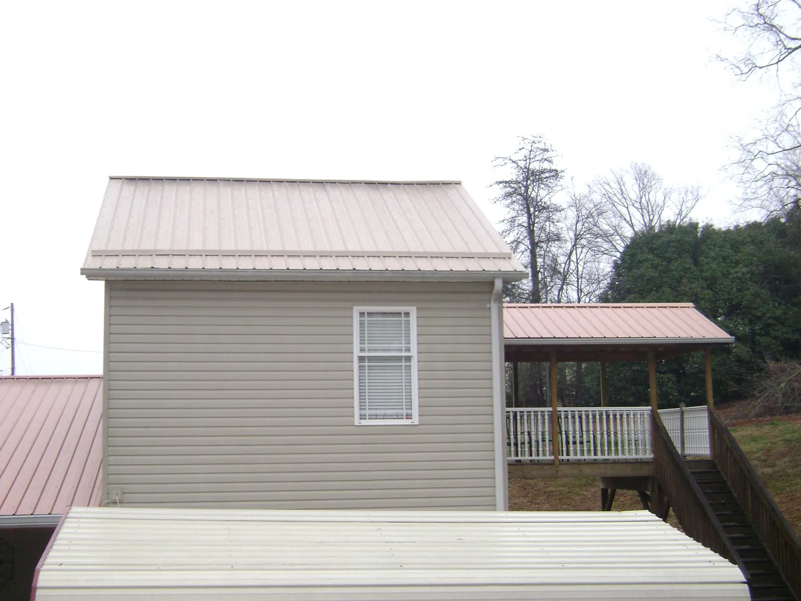 Tan metal roofs on a two story addition and attached porch, from a Roof Replacement job in Glendale Heights