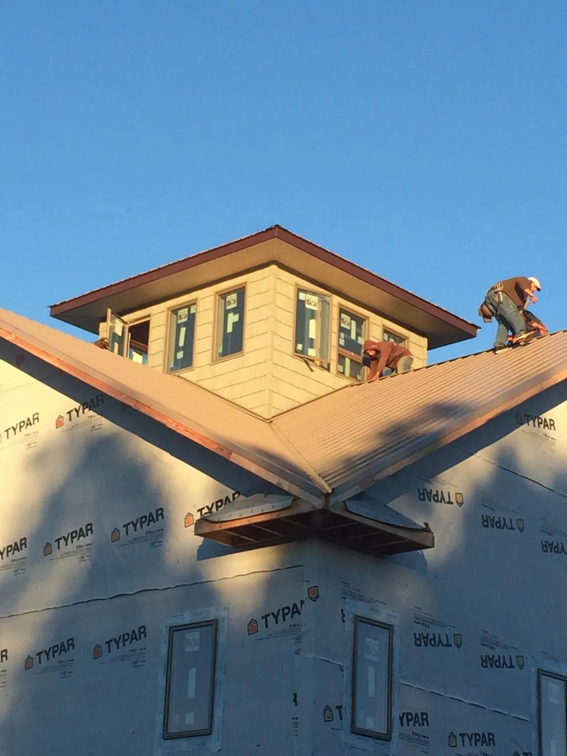 Roofers working around a rooftop cupola on a new metal roof at sunset — Roof Waterproofing in Glendale Heights by Roofing Brothers